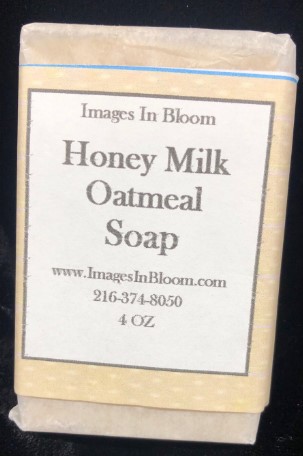 A bar of Honey Milk Oatmeal Soap wrapped in simple packaging, featuring a label that includes the product name, website, and contact number.