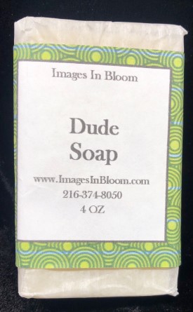 A bar of soap labeled 'Dude Soap' with a decorative green and yellow patterned band, featuring the website and contact information.