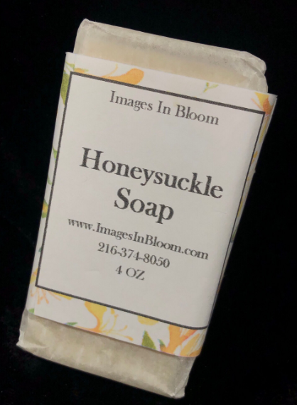 A wrapped bar of honeysuckle soap, featuring a label with the product name, website, phone number, and weight.