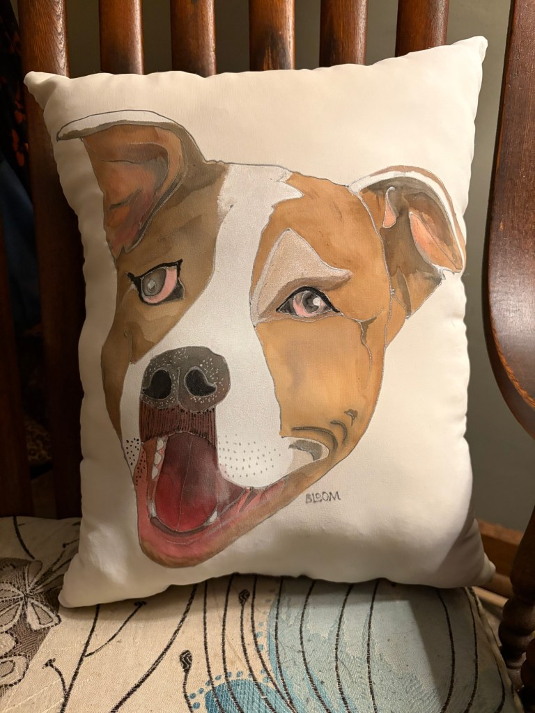A decorative throw pillow featuring an artistic illustration of a dog with a happy expression, primarily in shades of brown and white, sitting on a wooden chair.